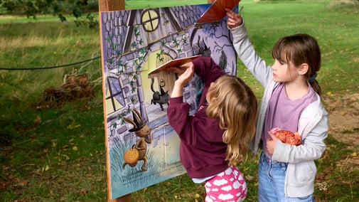 Two girls lift flaps on an activity board at The Vyne.